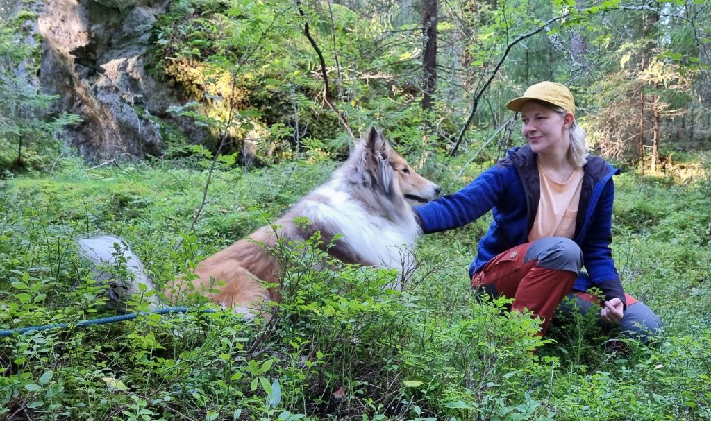 Johanna Puumala on metsässä koiransa kanssa.
